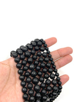 Shungite gemstone beads on hand for size reference