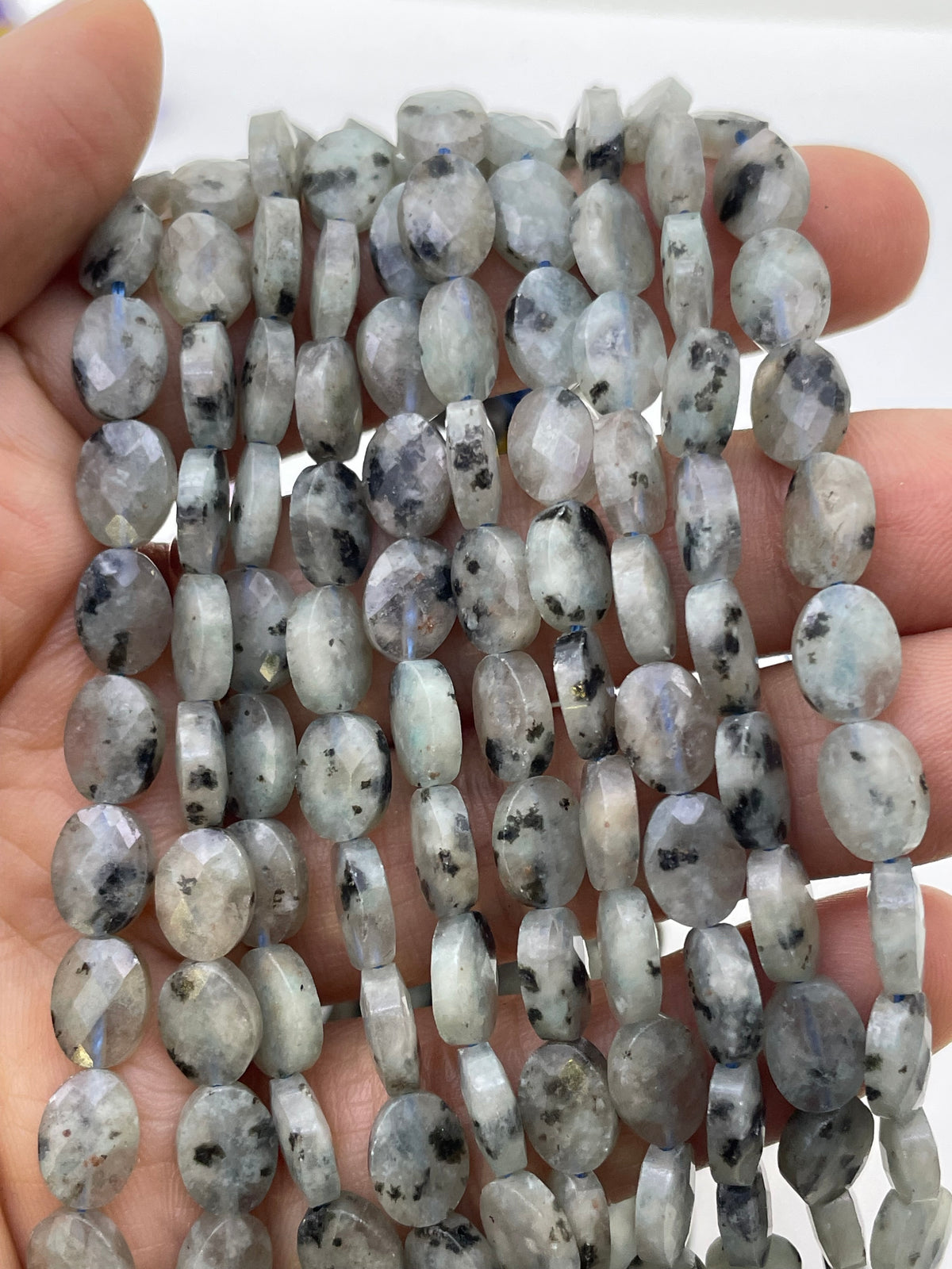 Flat oval faceted kiwi jasper on a hand for size reference