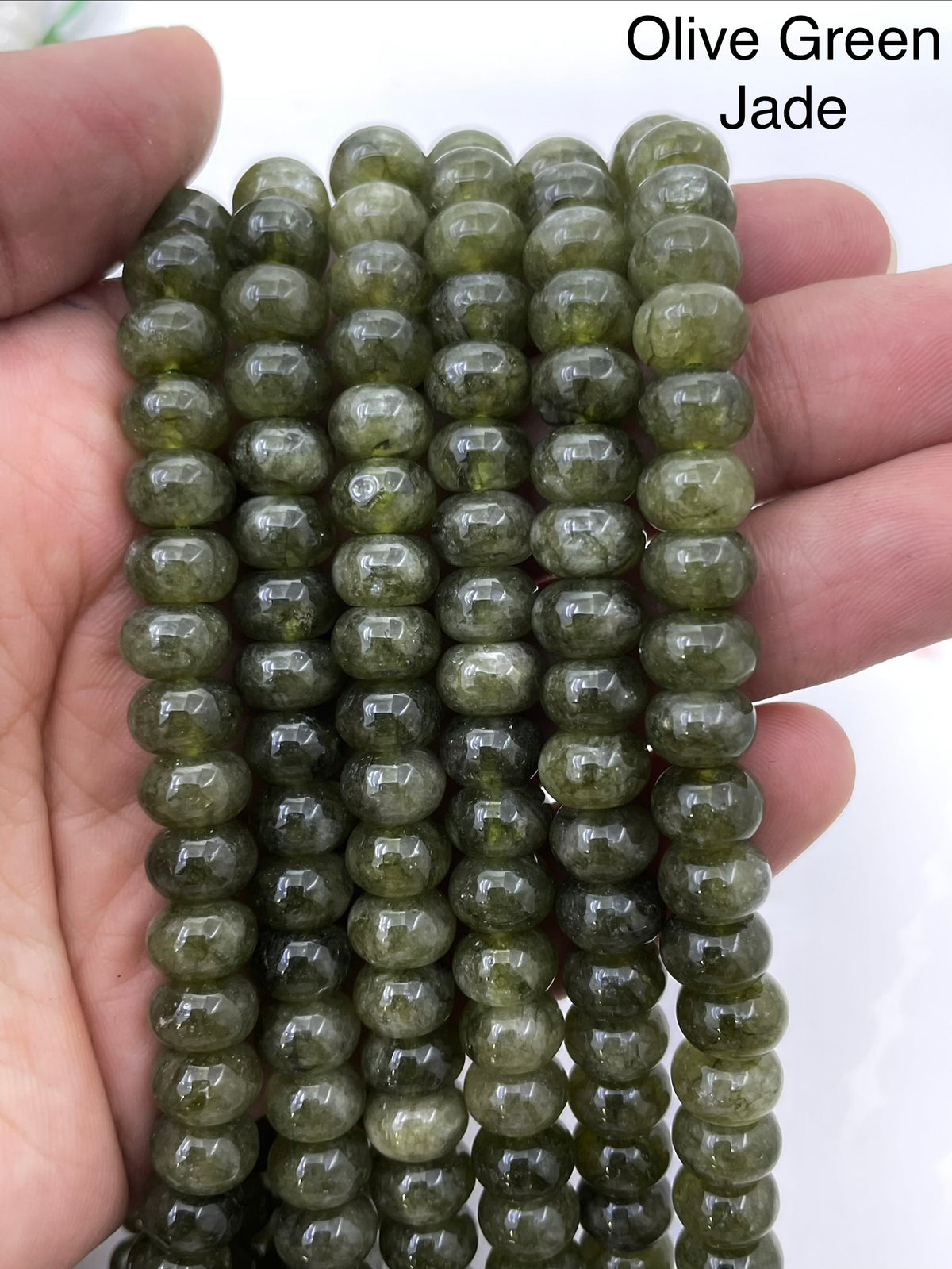 Olive green jade on a hand for size reference
