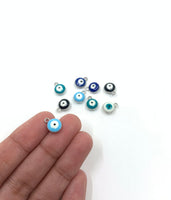 Evil eye charms shown on hand for size reference.