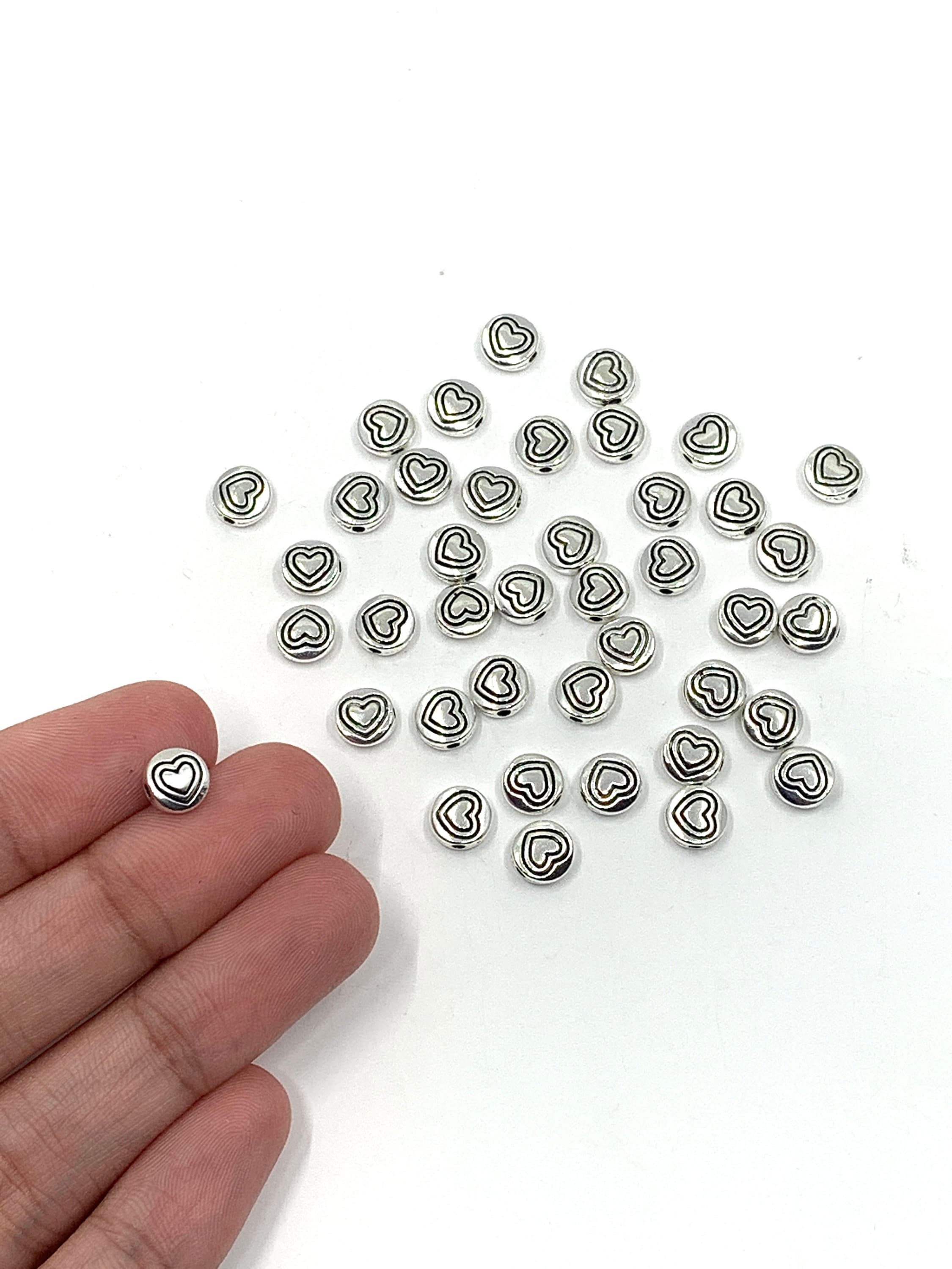 Heart beads shown on hand for size reference