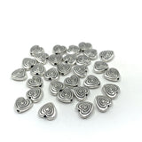 Heart shaped alloy spacer beads against a white background
