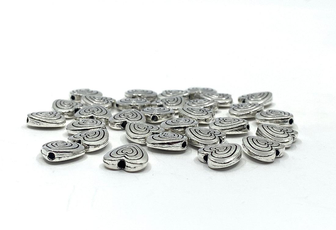 Heart shaped alloy spacer beads against a white background